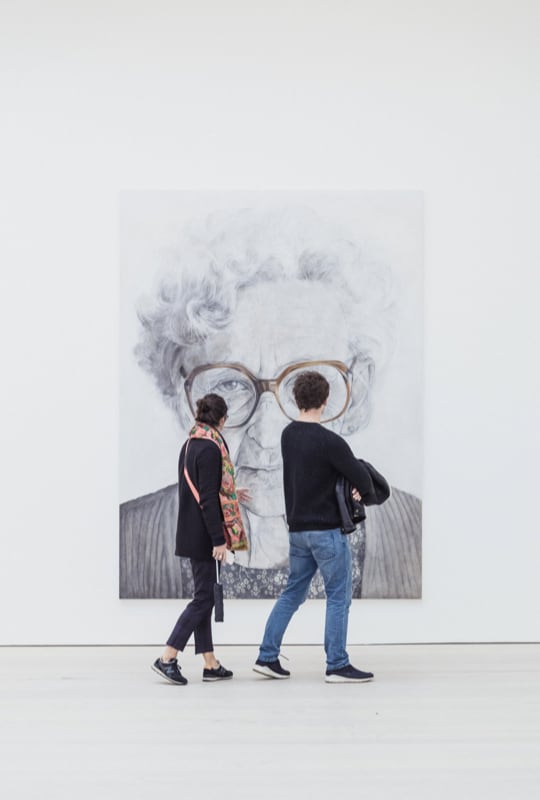 two people standing in front of a painting