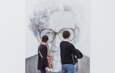 two people standing in front of a painting