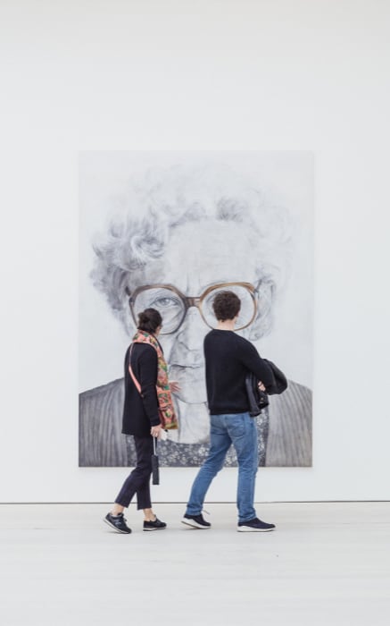 two people standing in front of a painting